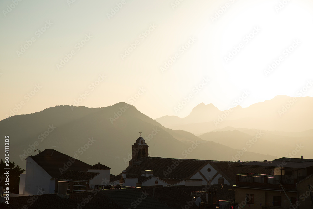 A view over a small Spanish town with mountains and a church with a cross