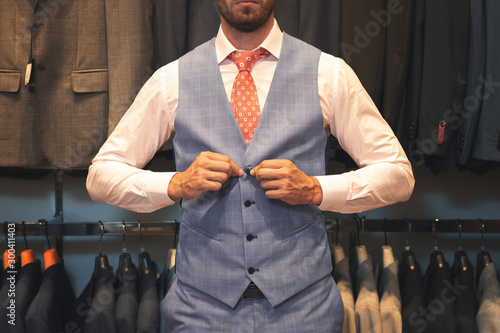 Fototapeta businessman in suit buttoning waistcoat