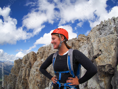 attractive brunette female climber on a mountain peak in the Dolomites looking to the distance
