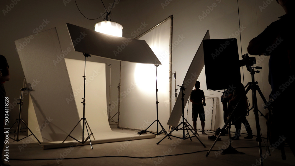 Silhoutte images of video production and lighting set for filming which movie crew team working and silhouette shadow of camera and professional equipment in big studio for commercial advertising. - obrazy, fototapety, plakaty 