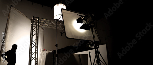 Silhoutte images of video production and lighting set for filming which movie crew team working and silhouette shadow of camera and professional equipment in big studio for commercial advertising.