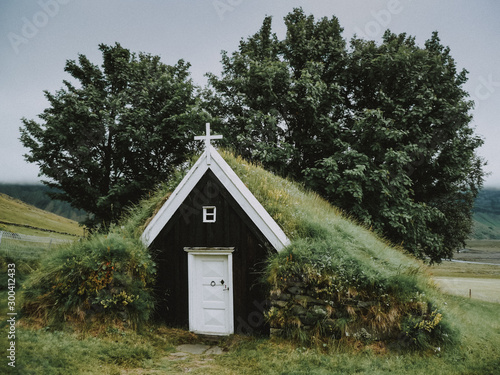 Vintage old wooden chapel covered by grass with tree backround in Nupstadur in Iceland