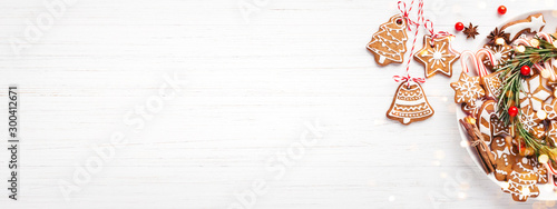 Plate with Christmas gingerbread cookies decorated with wreath made of rosemary on white table. Top view, copy space., banner for website.