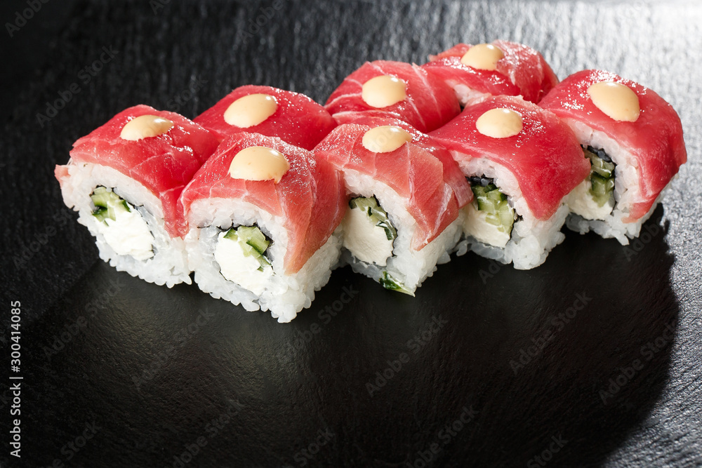 Sushi Rolls with cucumber, tuna, and Cream Cheese inside on black slate isolated. Philadelphia roll sushi with shrimp. Sushi menu. Horizontal photo. Sushi Rolls with cucumber, tuna, and Cream Cheese inside on black slate isolated. Philadelphia roll sushi with shrimp. Sushi menu. Horizontal photo.