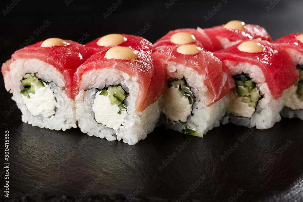 Sushi Rolls with cucumber, tuna, and Cream Cheese inside on black slate isolated. Philadelphia roll sushi with shrimp. Sushi menu. Horizontal photo. Sushi Rolls with cucumber, tuna, and Cream Cheese inside on black slate isolated. Philadelphia roll sushi with shrimp. Sushi menu. Horizontal photo.