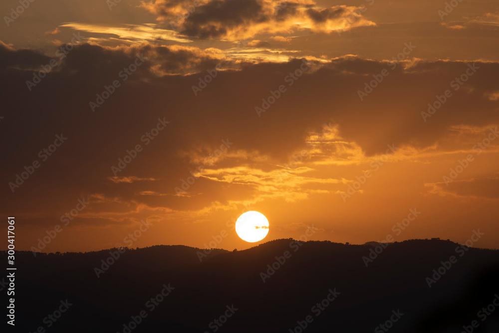 A beautiful dark yellow sunset with some scattered clouds and mountains 