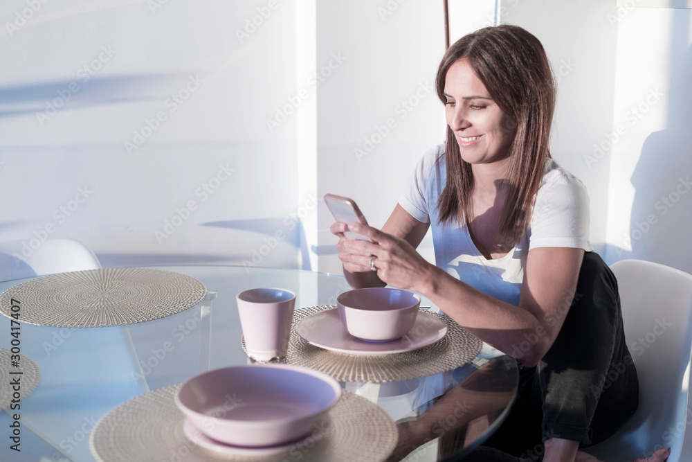 Attractive adult woman sitting at living room while using mobile phone Attractive adult woman sitting at living room while using mobile phone