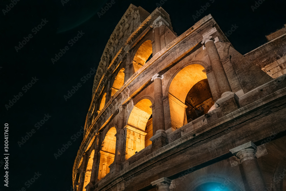 Colosseum, or Coliseum wall with night illumination. Huge Roman amphitheatre in Rome, Italy.