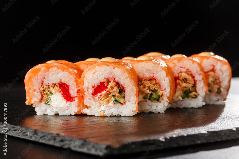 Sushi Rolls with flying fish caviar , fried onion, salmon and Cream Cheese inside and on black slate isolated. Philadelphia roll sushi with shrimp. Sushi menu. Horizontal photo. Sushi Rolls with flying fish caviar , fried onion, salmon and Cream Cheese inside and on black slate isolated. Philadelphia roll sushi with shrimp. Sushi menu. Horizontal photo.
