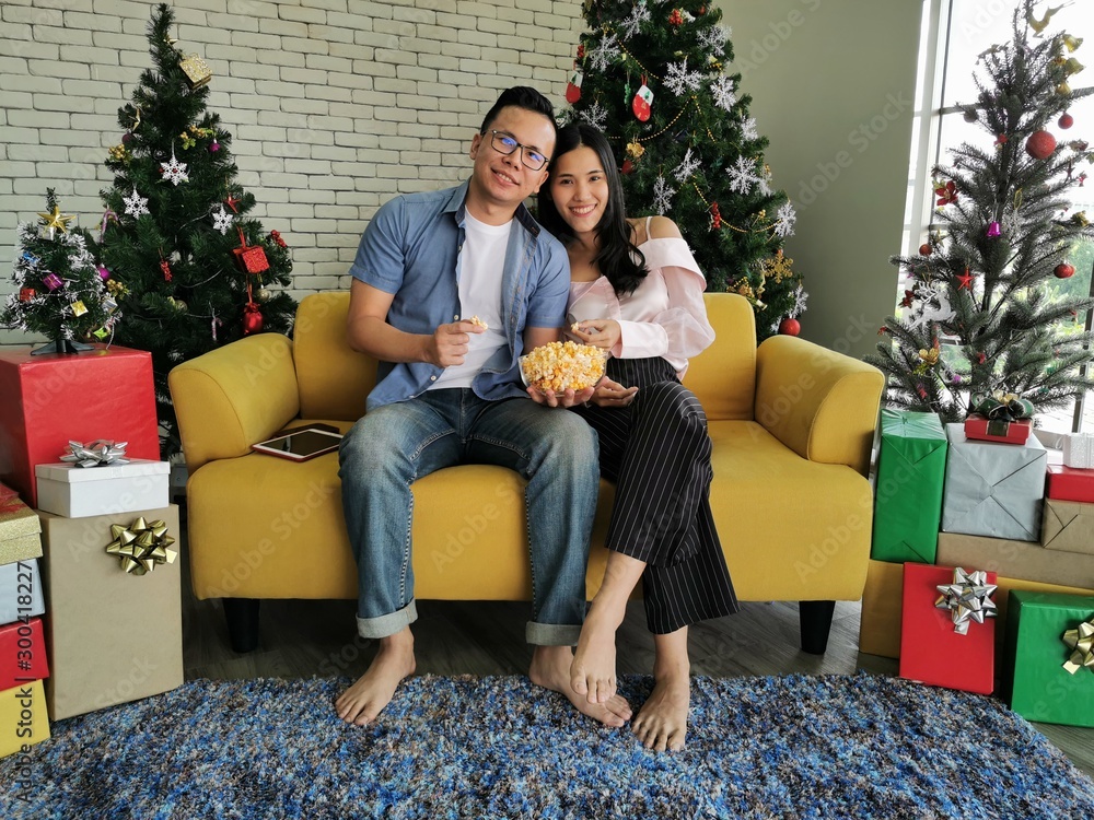 young couple with gift in front of christmas tree