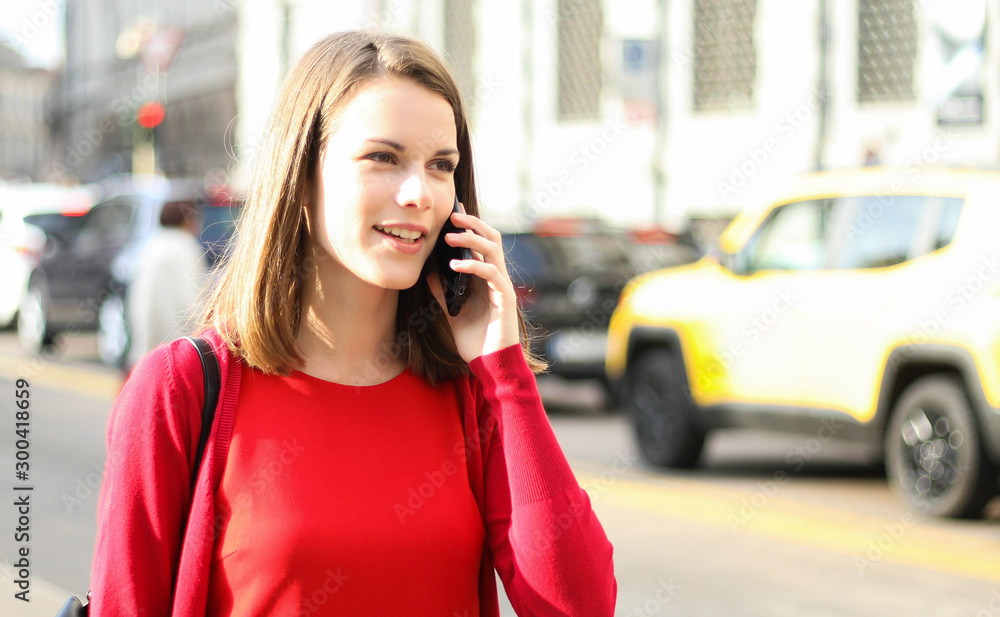 Young woman walking in the city in casual cloths and talking on the phone