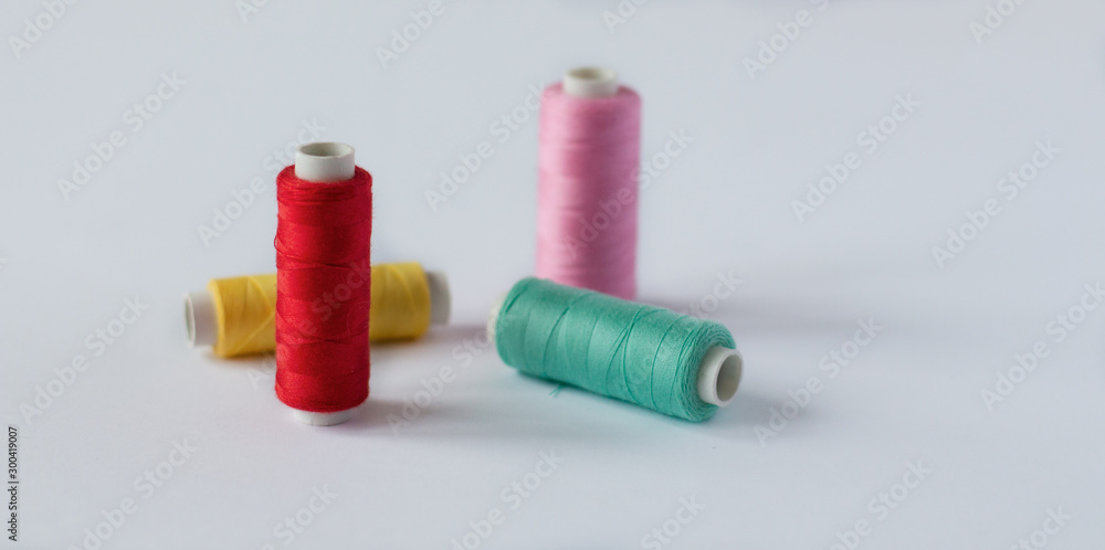 Many bobbins of bright sewing thread with a soft pink background isolated Many bobbins of bright sewing thread with a soft pink background isolated