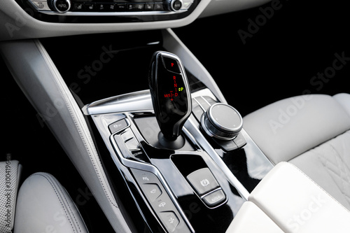 Automatic gear stick of a modern car. Modern car interior details. Close up view. Car detailing. Automatic transmission lever shift. White leather interior with stitching.