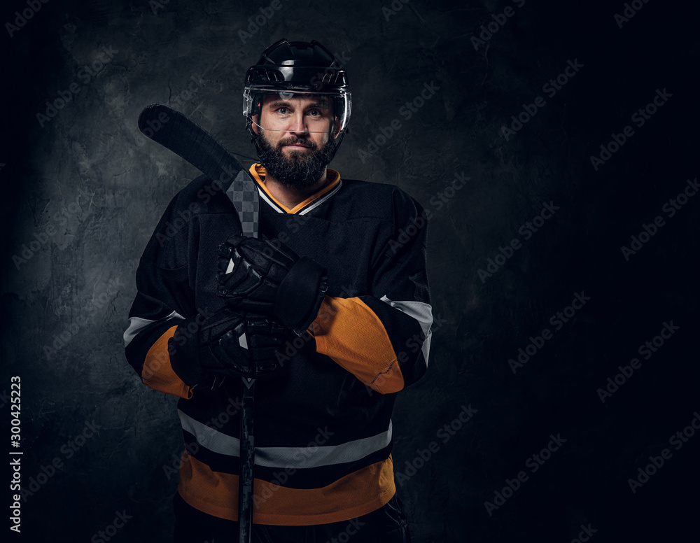 Professional bearded man in hockey player gear is posing for photographer.