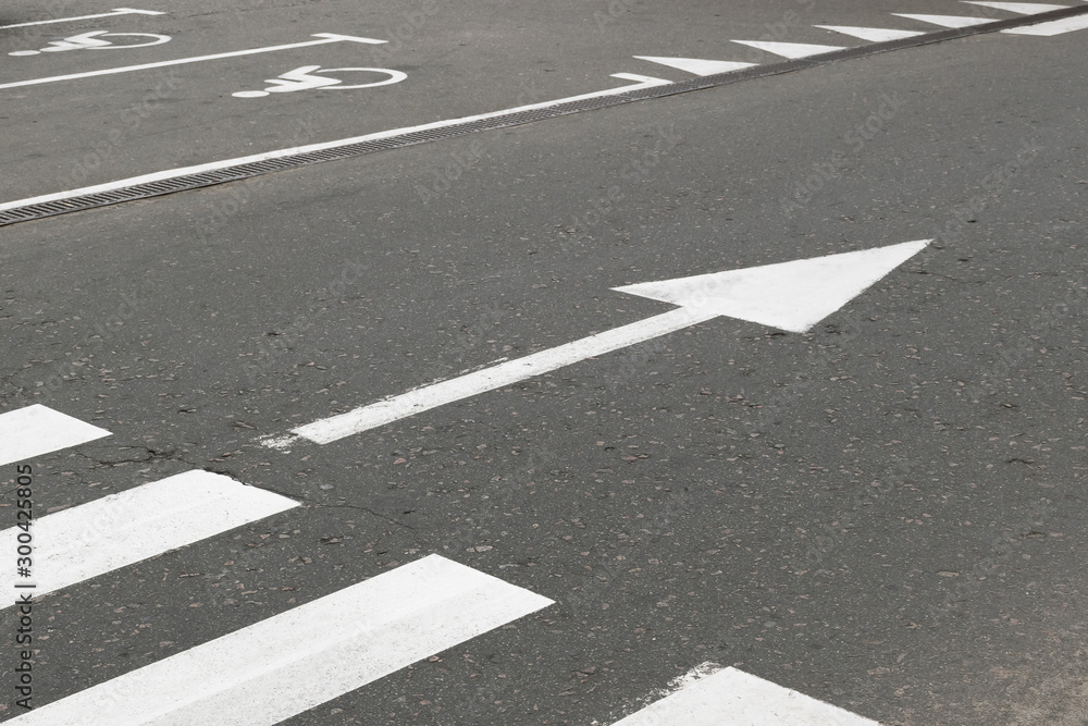 Road marking on asphalt with direction of movement and pedestrian crossing Road marking on asphalt with direction of movement and pedestrian crossing