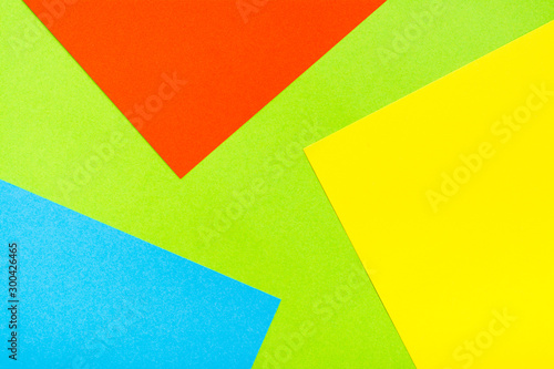 Four-color yellow green red blue abstract cardboard background. Sheets of cardboard are stacked on top of each other. Copy space