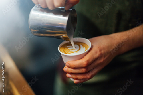 Barista making coffee in coffee shop, hands holding cup of coffee. photo