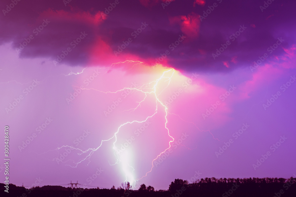 A lightning strike on the cloudy sky. Pink, lilac and purple toned image