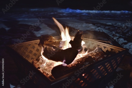 Fototapeta Naklejka Na Ścianę i Meble -  Flames under the stars crate a meditative mood as wood is burning amd creating a soft ambiance in a fire pit
