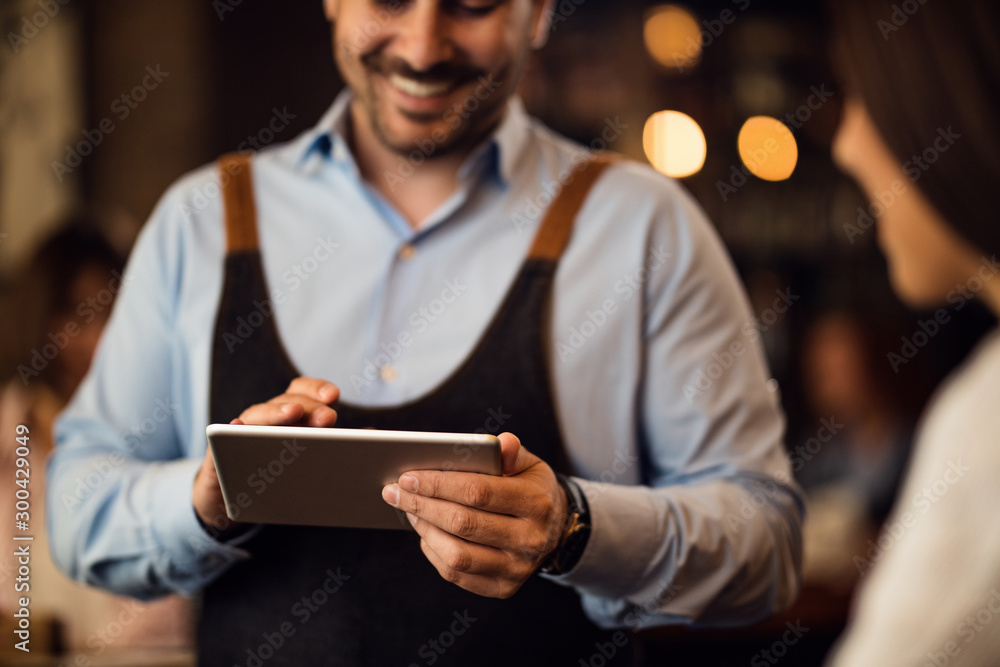 Close-up of waiter taking an order on touchpad in a bar. Close-up of waiter taking an order on touchpad in a bar.