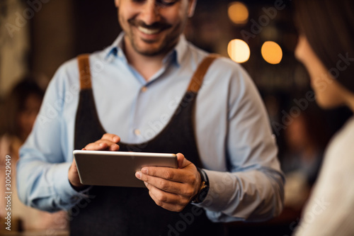 Close-up of waiter taking an order on touchpad in a bar.