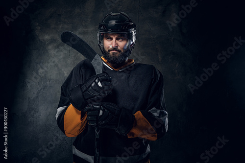 Serious pensive hockey player has a photo session at photo studio.