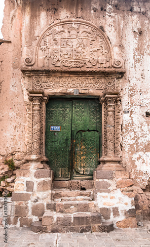 Entrance door of a clay house with decoration in relief on a street of Juli city  Puno region  Peru