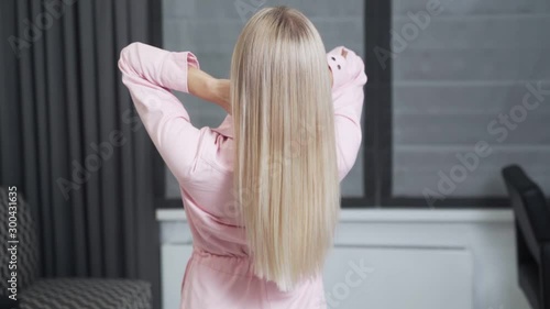 Slow-motion shooting of a long blond hair of a young girl, backside view