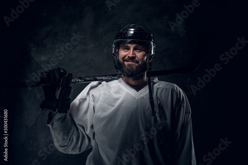 Confident emotional hockey player with hockey stick is posing for photographer. © Fxquadro