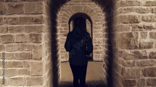 Woman walking through archway doors of castle // following shot photo