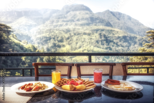 Breakfast in restaurant with beautiful view on mountains range in summer sunny morning during travel holidays