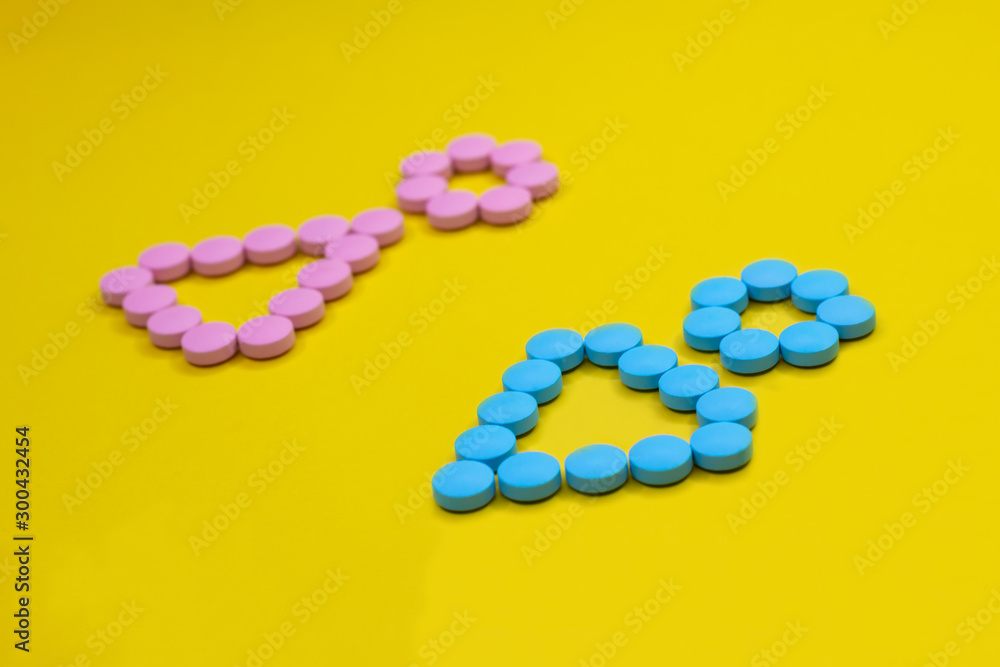 male and female symbols made from pink and blue pills on yellow background.