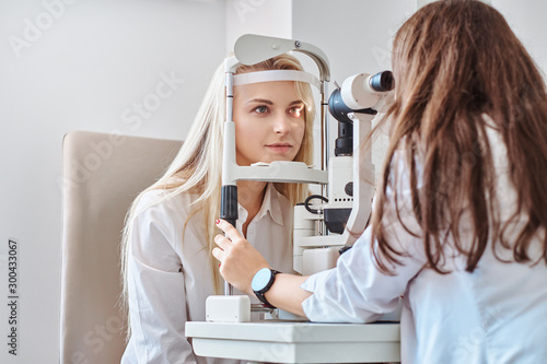 Fotografia Attractive woman is doing eye test in optical clinic with experienced oculist