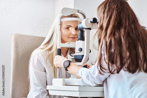Attractive woman is doing eye test in optical clinic with experienced oculist. photo