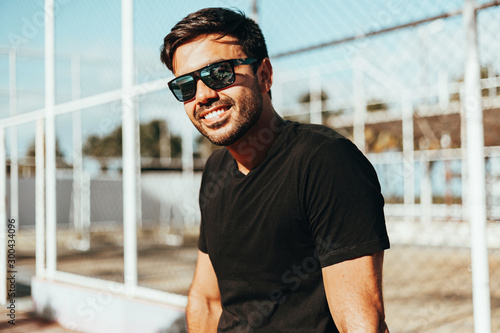 Portrait of smiling man wearing sunglasses and t-shirt enjoying a sunny summer day in the city