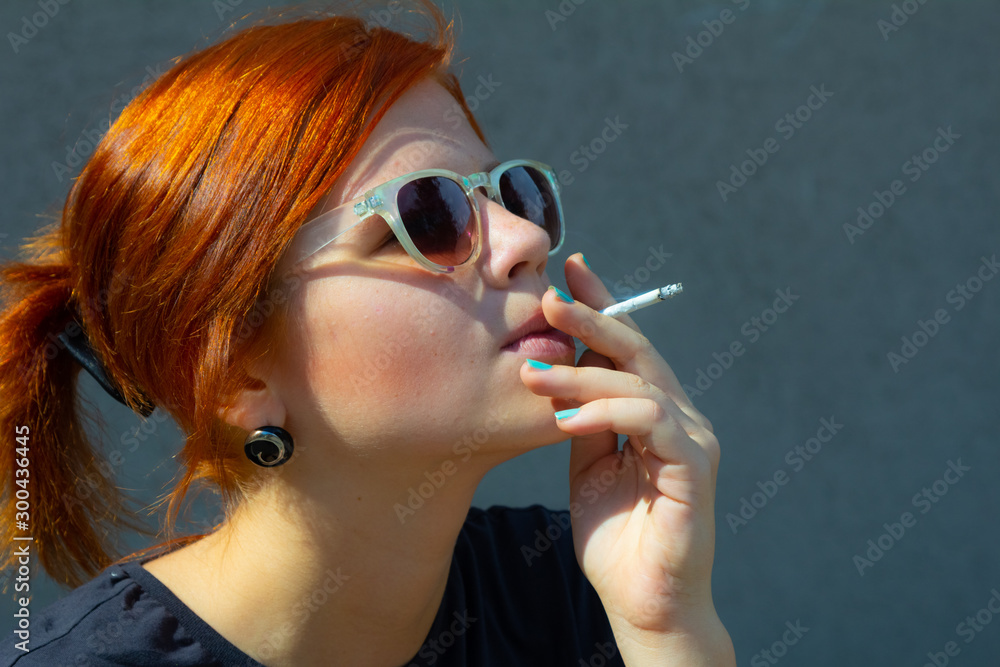 Obraz premium girl smokes a cigarette, and holds a cigarette in her hand