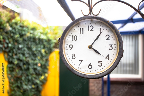 Antique vintage style clock hanging outside, hanging on the wall of a house