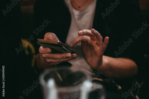 Closeup image of female hands using smartphone in cafe in the evening social networks concept, hipster man typing sms message to his friends