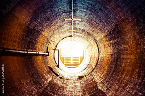 Fototapeta Wpatrując się w stary tunel ze światłem na końcu tunelu. To jest tunel wentylacyjny w zaporze Hoovera.
