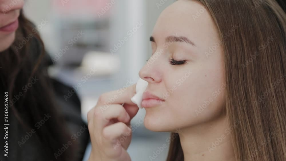 Professional makeup artist wipes a client with a cotton pad dipped in a special gel. Professional makeup artist wipes a client with a cotton pad dipped in a special gel.