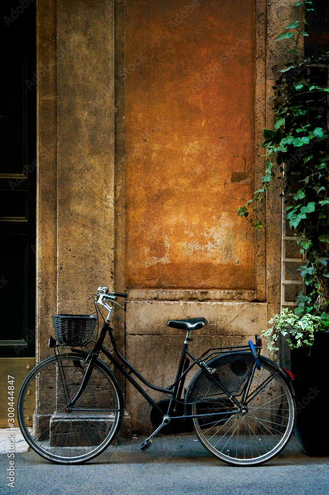 Old bicycle leaning against an old rustic, weathered wall in Rome, Italy.