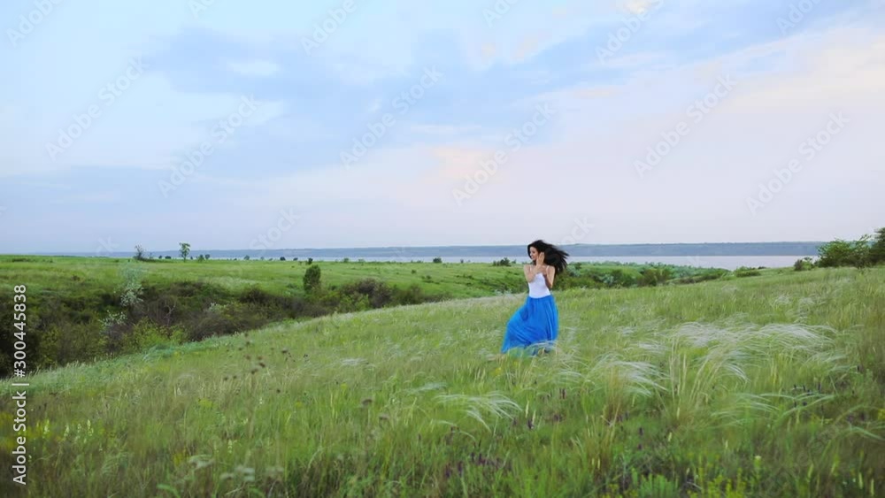 Graceful lady in long chiffon skirt puts up hands showing ballet moves among endless wheat under clear sky slow motion Graceful lady in long chiffon skirt puts up hands showing ballet moves among endless wheat under clear sky slow motion