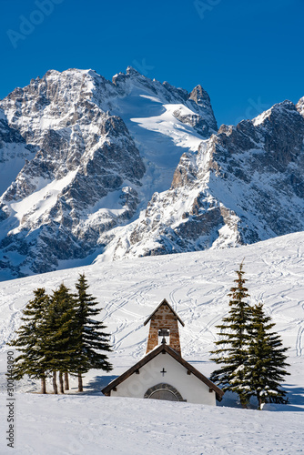 Winter view of the glaciers and mountain peaks of the Ecrins National Park (La Meije and Lautaret Glacier) with La Chappelle des Fusillés. Col du Lautaret, Hautes-Alpes, Alps, France