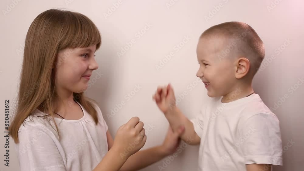 happy children wearing t-shirts play game rock paper scissor on white background, smile and laugh. boy and girl with playing together. little brother and elder sister have fun. small caucasian kids happy children wearing t-shirts play game rock paper scissor on white background, smile and laugh. boy and girl with playing together. little brother and elder sister have fun. small caucasian kids