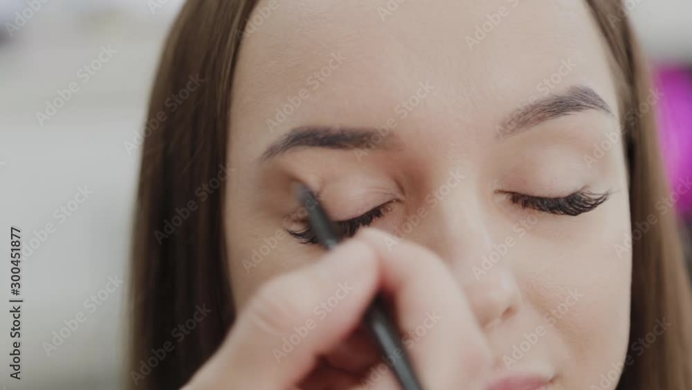 Professional makeup artist woman stirs makeup cream on a palette.