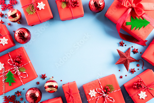 Christmas background concept. Top view of Christmas red gift box with candy cane  snowflakes  red berries and bell on blue pastel background.