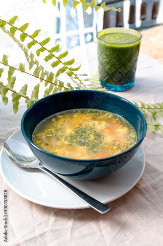 Zupa w niebieskiej misce z ziemniakami i napojem zielonym w restauracji lub stołówce na jasnym tle