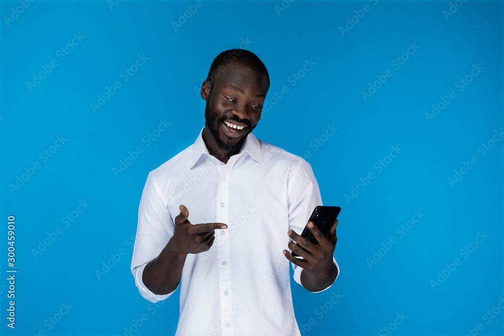 A smiling black man keeps the phone and looks at it A smiling black man keeps the phone and looks at it