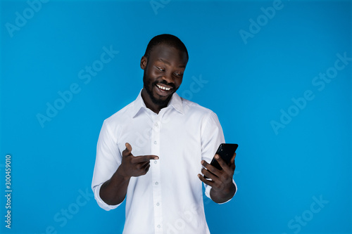 A smiling black man keeps the phone and looks at it photo