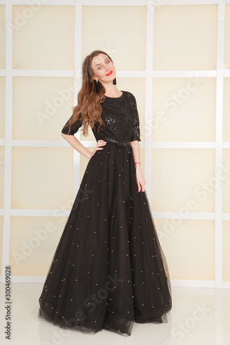 elegant slim adult woman in fashion long evening lace black dress on white studio background, full length body